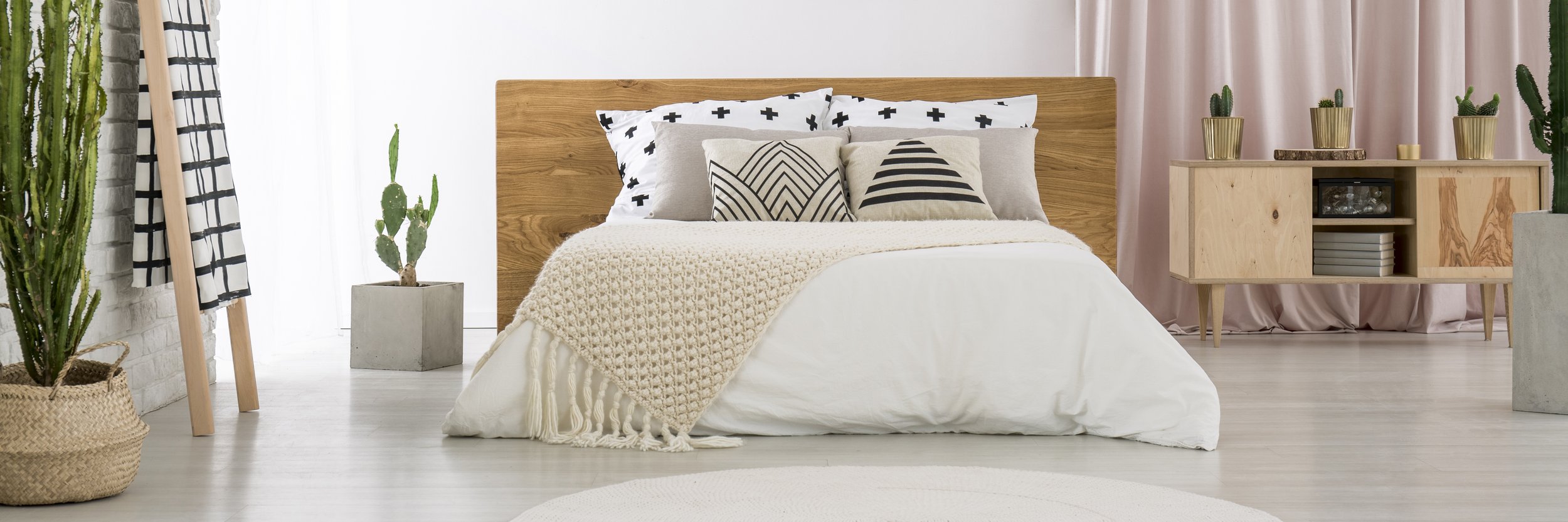 A wide-angle modern bedroom with white bedding